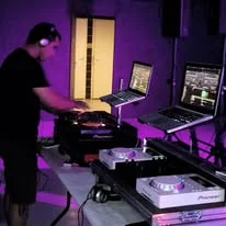DJ au casque en plein mix avec platines et écrans